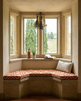 Rust patterned cushion on a bay window seat with a vineyard view