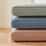 Stacked boucle cushions in sage, blue and blush