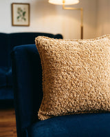Camel boucle pillow on a navy velvet chair
