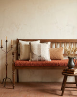 Rust cushion with patterned pillows on a wooden settle