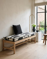 Black and white geometric cushion on an oak bench